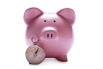 Pink piggy bank next to a vintage compass