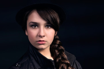Portrait of a beautiful girl with a plait and wearing a hat