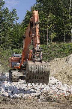Working excavator during the removal of stones from the destroye