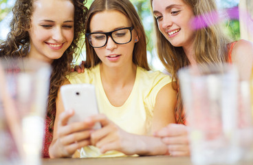 Girls having fun with smartphone in pub