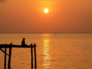 Meditation man on wooden pier under sunset sea