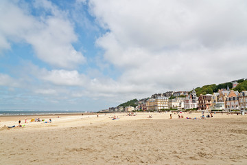 Beach with tourists and houses at Deauville with blue cloudy sky