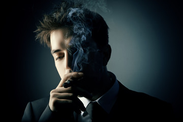 Young handsome stylish man smoking cigar