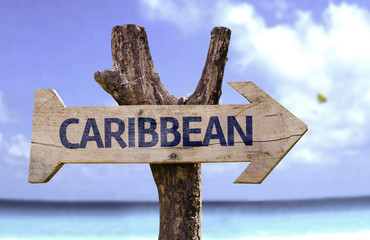 Caribbean wooden sign with a beach on background