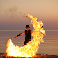 Fire performer with a torch on sunset background