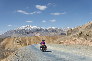 Couple on motorbike riding among mountains