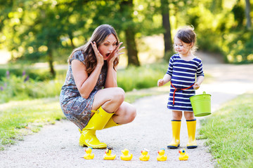 Mother and little adorable child in yellow rubber boots