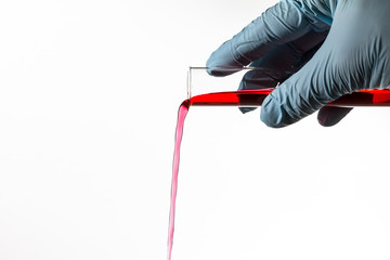 Scientist pours red liquid out of a test tube, isolated on white