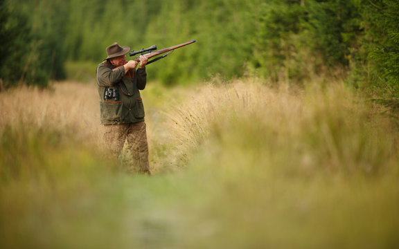 hunter with his rifle in spring forest, hunter holding a rifle