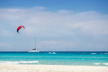 Beach with yacht and kitesurfer in Sardinia