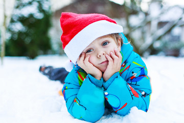 Happy little toddler boy waiting for Christmas santa hat