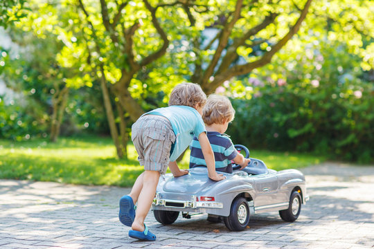 Two happy children playing with toy car