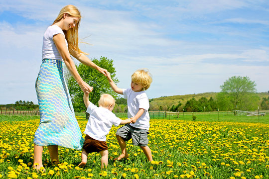 Mother and Children Playing and Dancing Outside in Flower Meadow