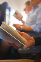 People reading books in the airplane. Detail.