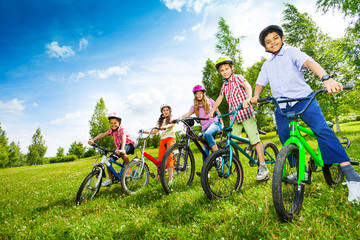 Row of children in colorful helmets holding bikes