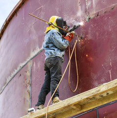 worker with protective mask welding metal and sparks