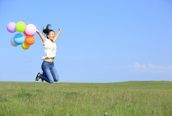 Fototapeta premium young asian woman on green grassland with colored balloons 