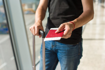 Obraz premium Man holding passports and boarding pass at airport while waiting