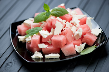 Salad with watermelon and cheese over black wooden background