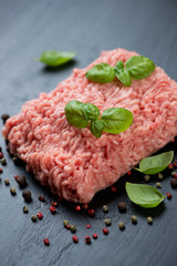 Close-up of minced turkey meat with fresh green basil and pepper