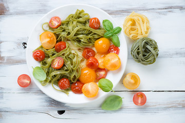 Colored tagliatelle with fried tomatoes and green basil