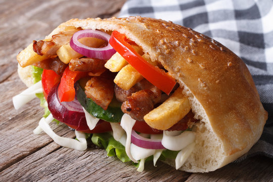 Doner with meat, vegetables and fries in pita bread close-up