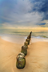 Krajobraz morski, plaża z drewnianym falochronem - obrazy, fototapety, plakaty