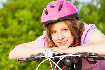 Naklejka premium Portrait of smiling girl in helmet on handle-bar