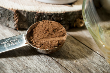 Brown chocolate powder on a spoon over a wooden table