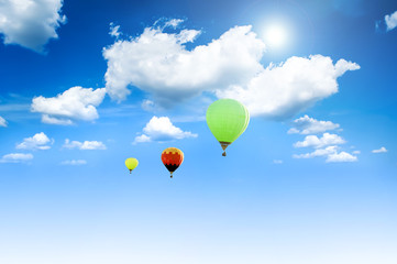 Fototapeta premium Balloons sunlit against a blue sky and clouds.