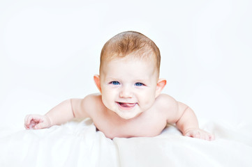 Happy kid put out his tongue is leaning on hands on a light back
