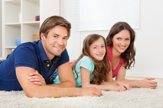 Family Lying Together On Rug At Home