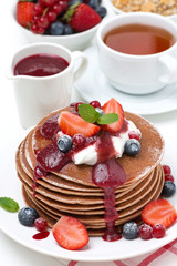 pancakes with cream, fruit sauce, berries and tea for breakfast