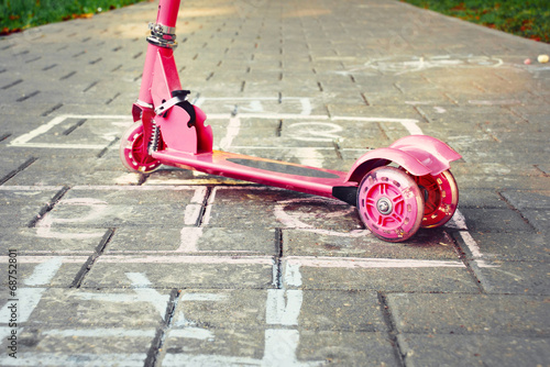 background of playground with pink little kid scooter and hopsco