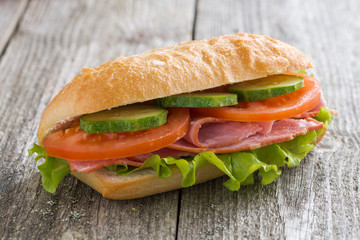 sandwich with ham and vegetables on wooden table