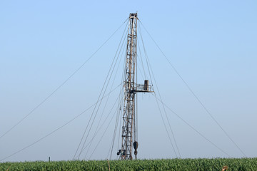 oil drilling rig behind wheat field