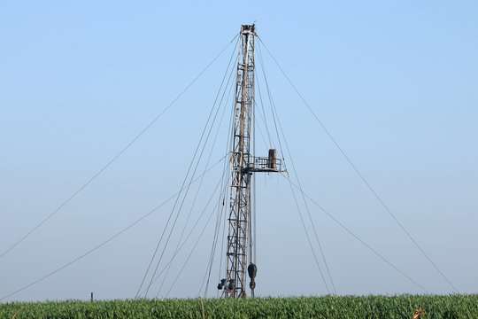 oil drilling rig behind wheat field