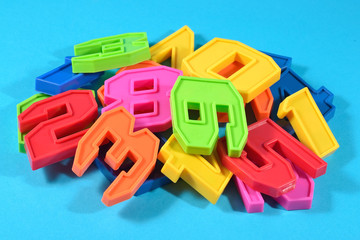 Heap of plastic colored numbers on a blue background