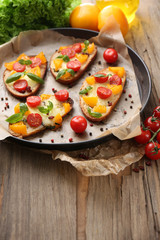 Tasty bruschetta with tomatoes on pan, on old wooden table