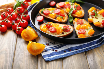 Tasty bruschetta with tomatoes on pan, on old wooden table