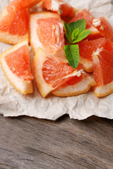 Ripe chopped grapefruit with mint leaves on wooden background