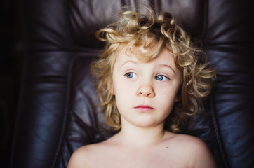 Sweet thoughtful little girl sits in armchair