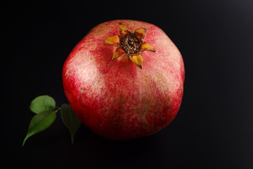 pomegranate fruit with leaves on black background
