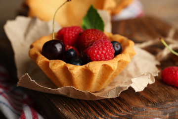 Tasty tartlets with berries on wooden table
