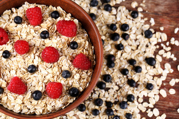 Big brown bowl with oatmeal and berries on a wooden table