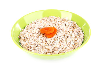Oatmeal in a green bowl with dried apricots isolated on white