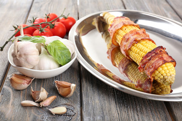 Grilled bacon wrapped corn on table, close-up