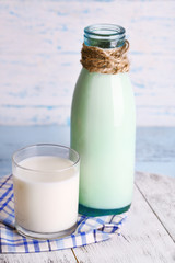 Glass bottle of milk on wooden background
