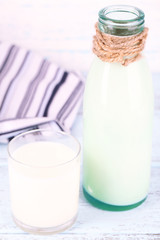 Glass bottle of milk on wooden background