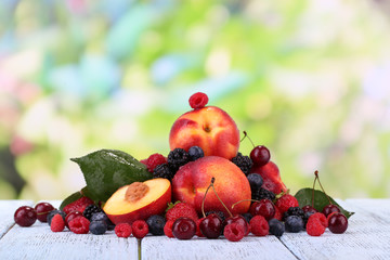 Peaches with berries on table on natural background